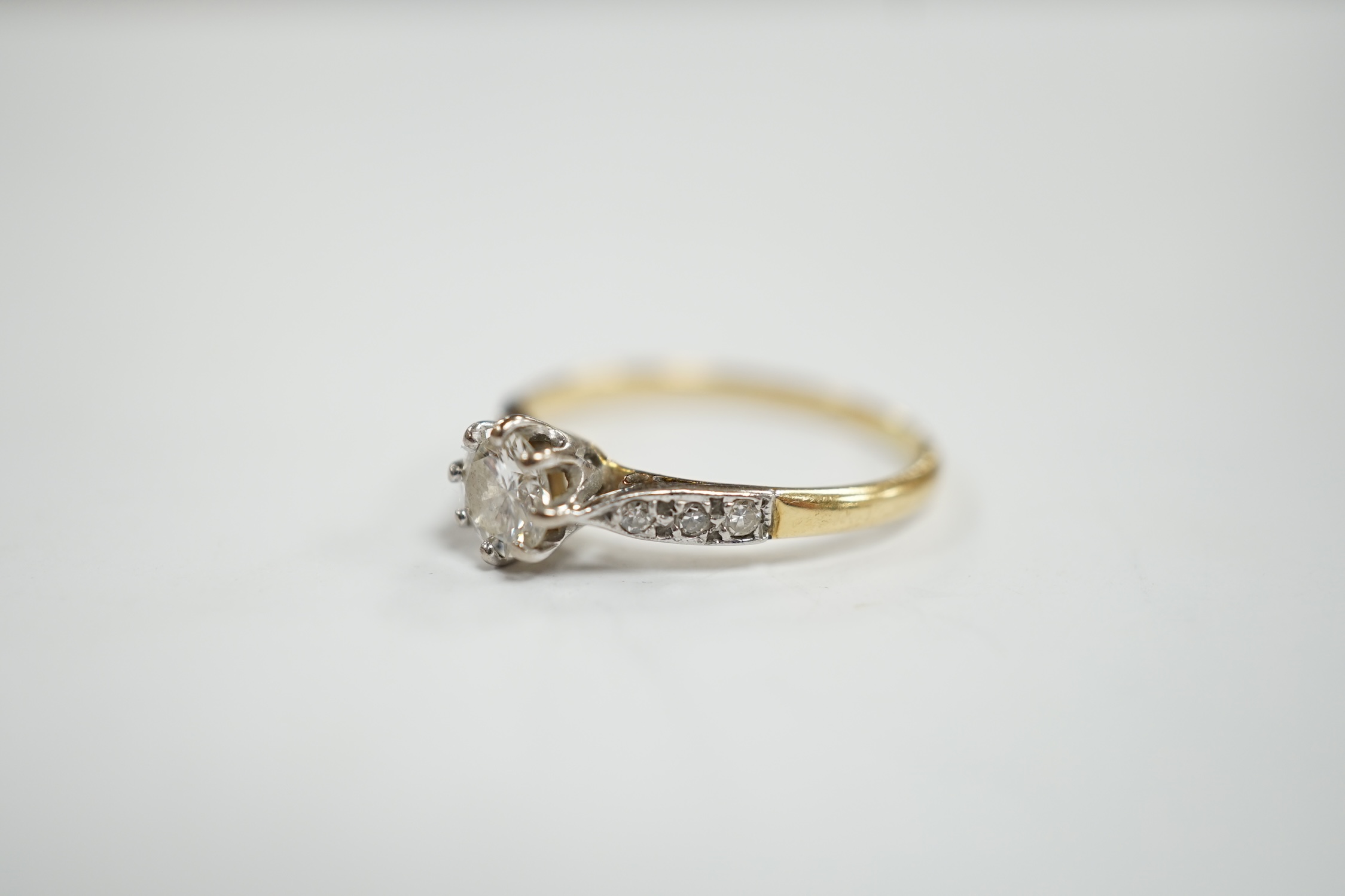 An 18ct and single stone diamond set ring, with diamond chip set shoulders, size M, gross weight 1.9 grams.